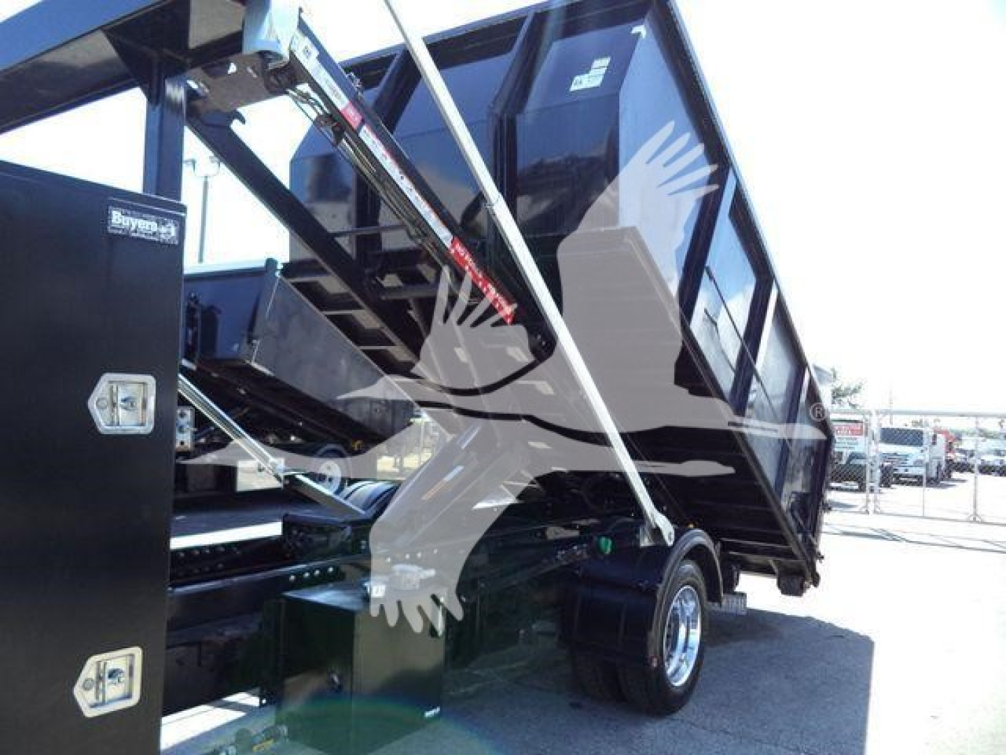 Truck side profile with a dump bed/rolloff mechanism, hydraulic arm and side-view cab visible; no clear legible labels or text readable on the image.