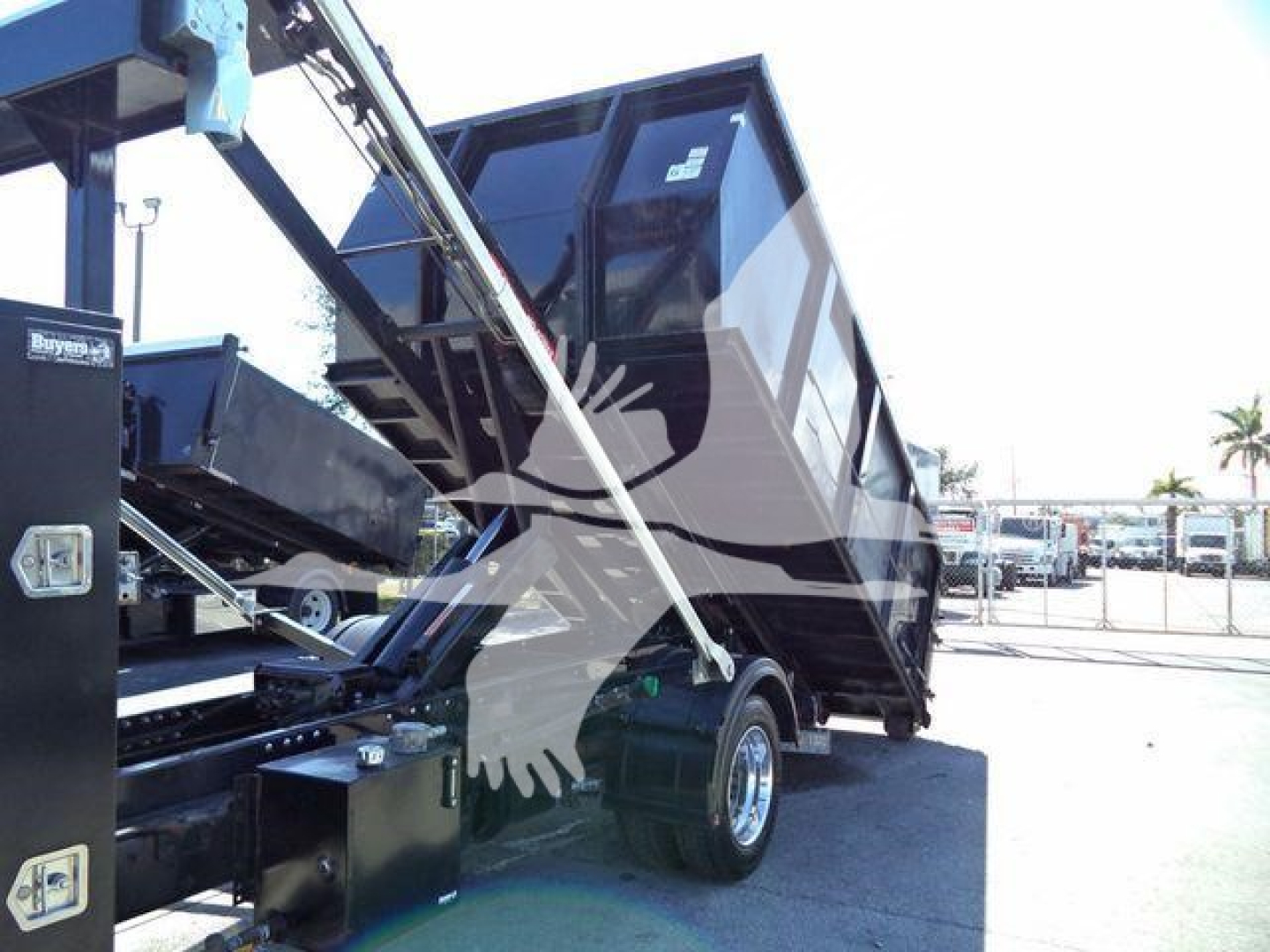 Truck bed tilting for a 2023 Chevrolet Silverado 6500HD rollback in an outdoor lot, with hydraulic mechanism and cargo bed raised.
