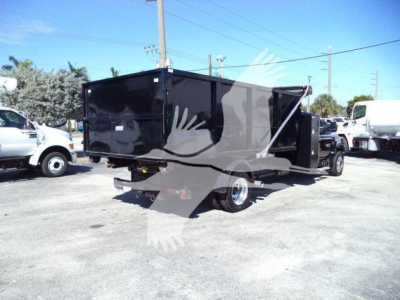 Truck bed with dump-style trailer attached in a lot; black hopper/dump container on a Silverado 6500HD chassis.