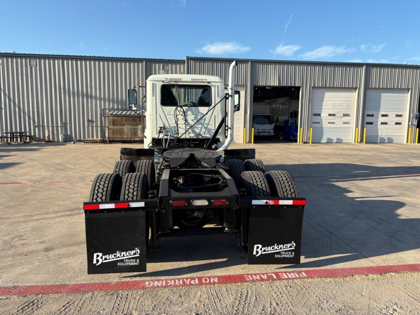 Rear view of 2020 Mack PI64T daycab truck chassis showing dual rear axles and rear mud flaps with Buckner's Equipment branding.