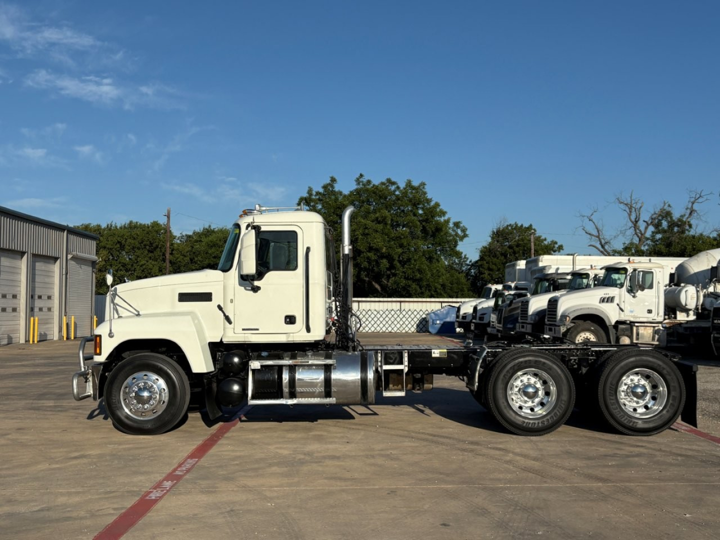 Truck chassis and cab of a 2020 Mack PI64T conventional daycab, side view, with dual rear axles and chrome fuel tanks visible