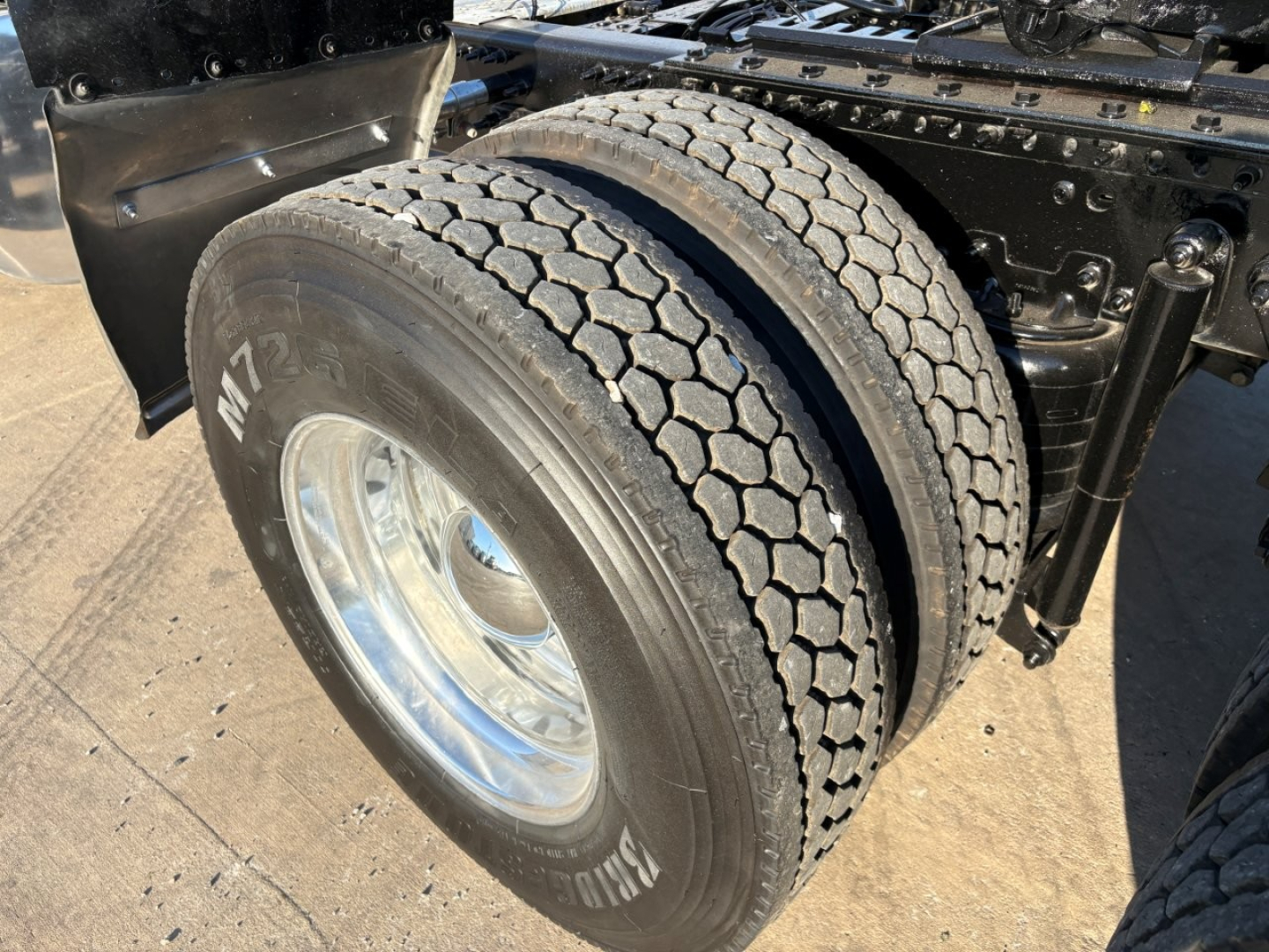 Wheel and dual rear tires of a Mack PI64T conventional daycab showing tread, rim, and frame with tires labeled M7 and pattern visible.