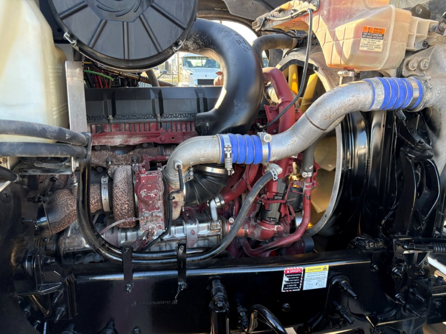 Mack PI64T engine bay showing turbocharger, intercooler piping, blue silicone hose, coolant reservoir, and supporting components.
