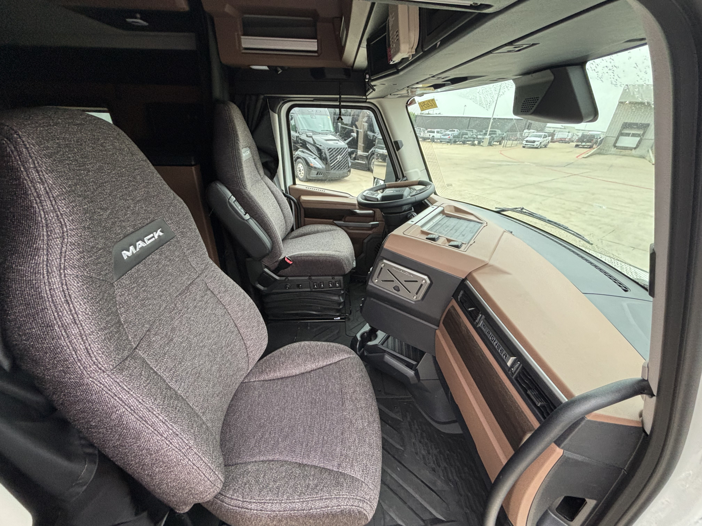Mack PR64T76M truck cab interior showing driver seat and dashboard with brown trim and steering wheel.