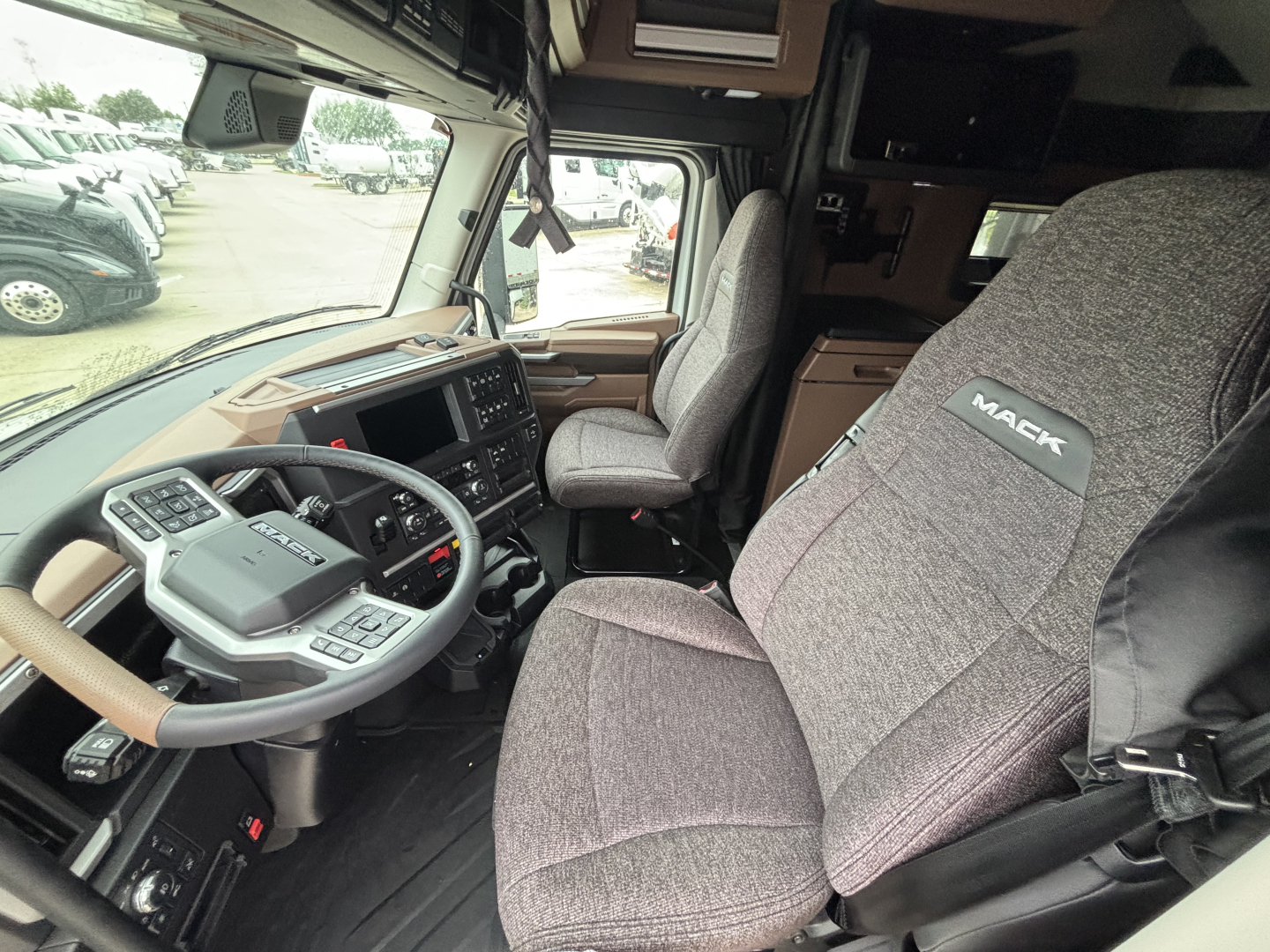 Mack PR64T76M truck cab interior showing steering wheel, dashboard, and Mack-branded seat.