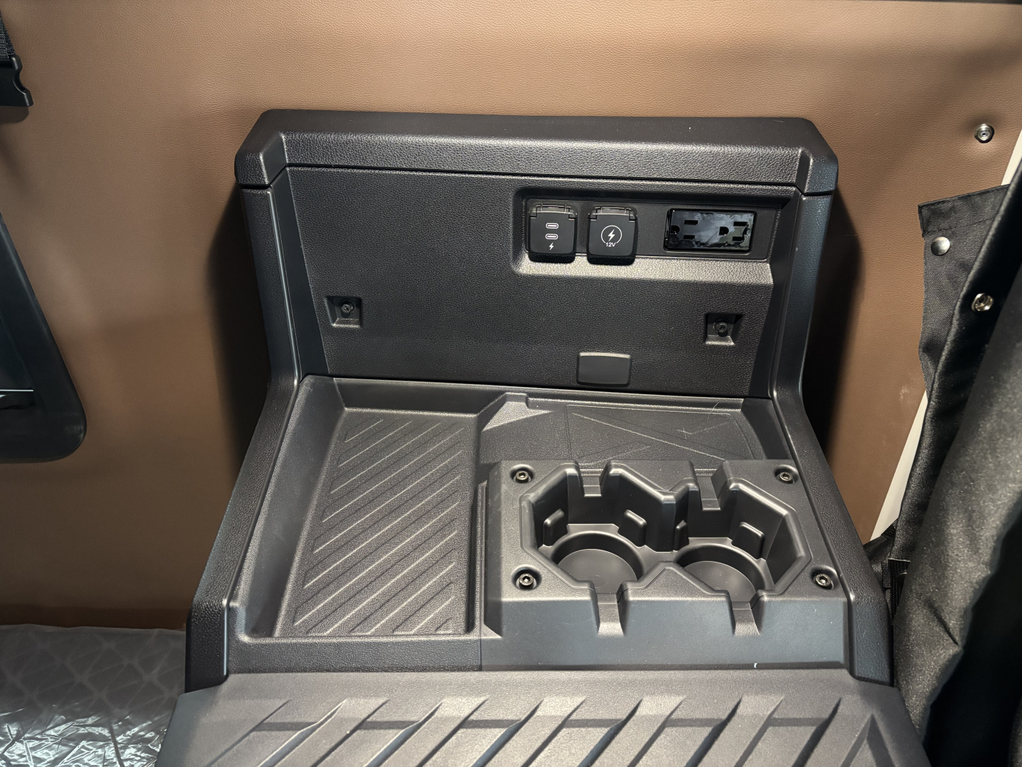 Truck interior center console showing cup holders and power/auxiliary ports panel.