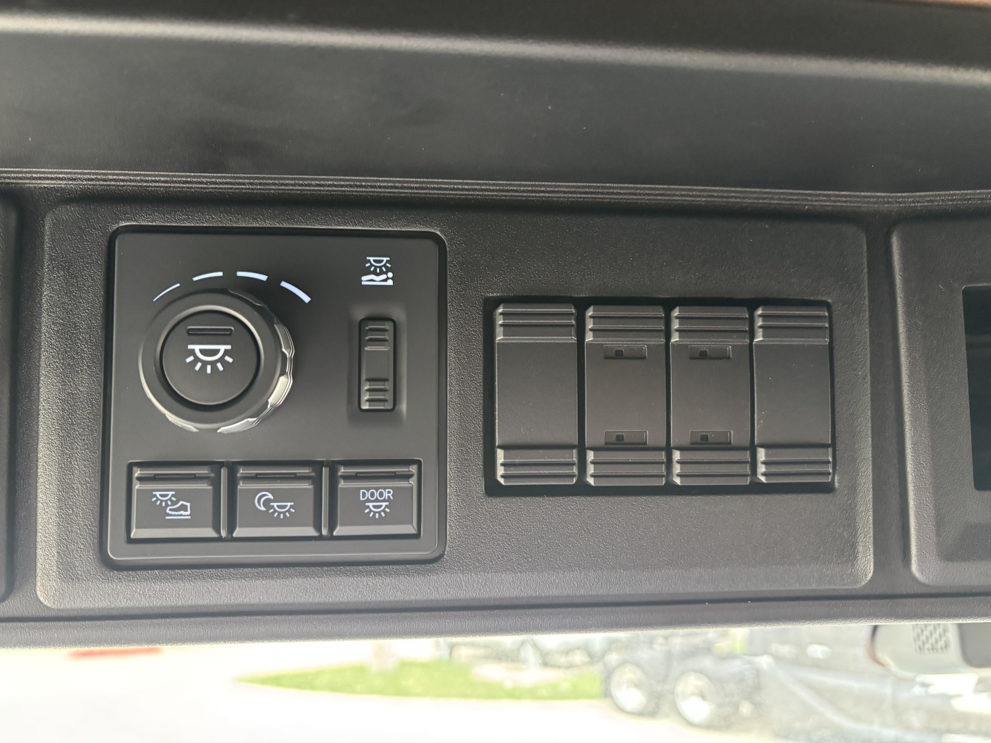 Truck dash panel showing headlight control knob and several blank switch panels.