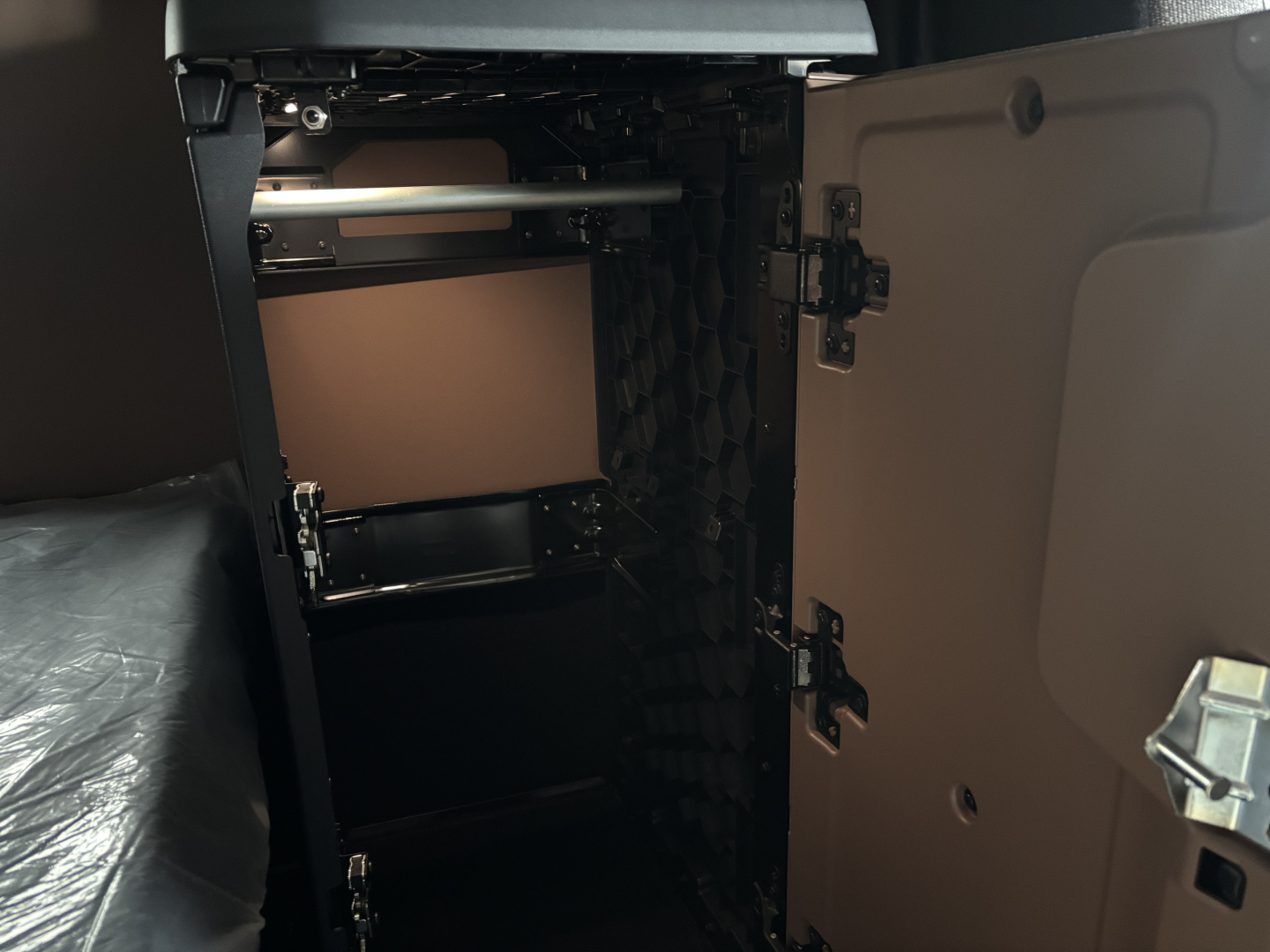 Truck cab interior showing storage cabinet inside sleeper, open cabinet door on right side, shelves and metal rod visible.