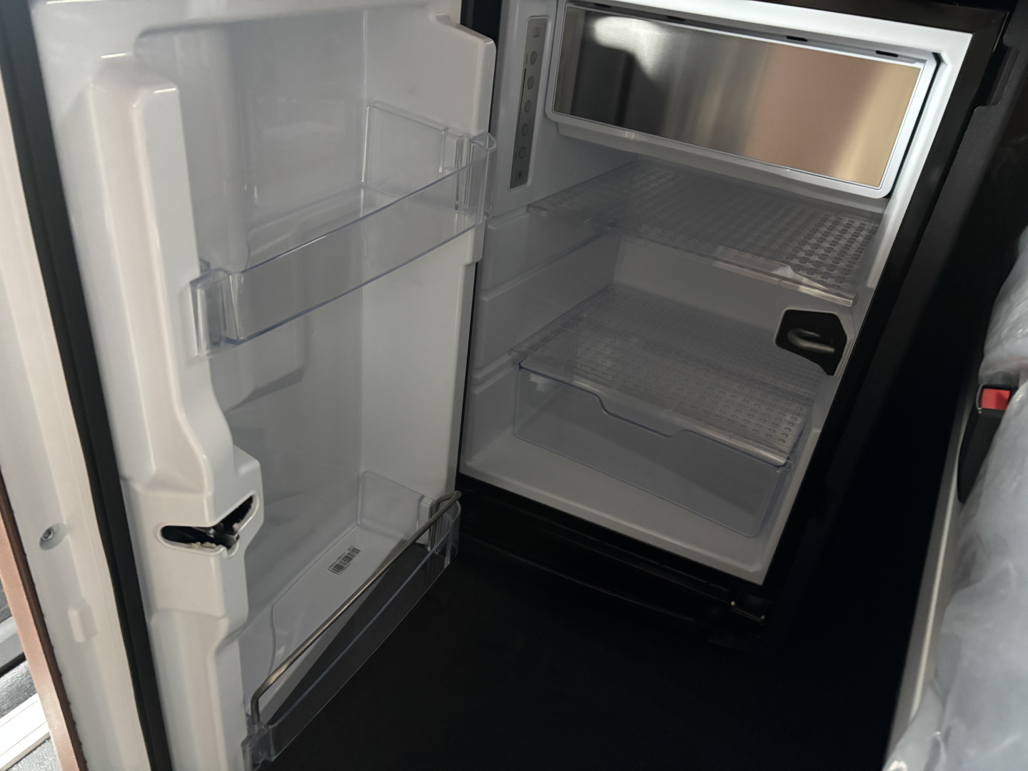 Fridge/freezer in a cab interior showing empty refrigerator shelves and door bins.