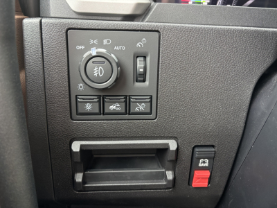 Truck dashboard control panel with headlight switch in center and several buttons below; small cubby/ashtray area and a red toggle switch labeled 'SAVE' on the right side.