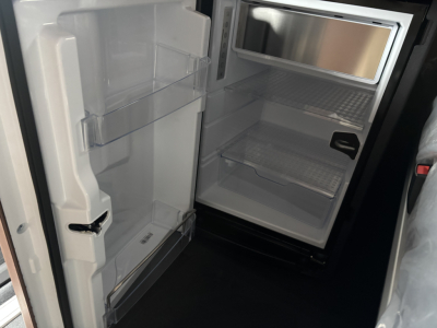 Fridge/freezer in a cab interior showing empty refrigerator shelves and door bins.