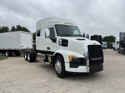 New 2027 Mack PR64T76M conventional sleeper truck shown in a dealership lot, front three-quarter view, white exterior, 6x4 tractor with dual rear axles, Mack emblem on grille.