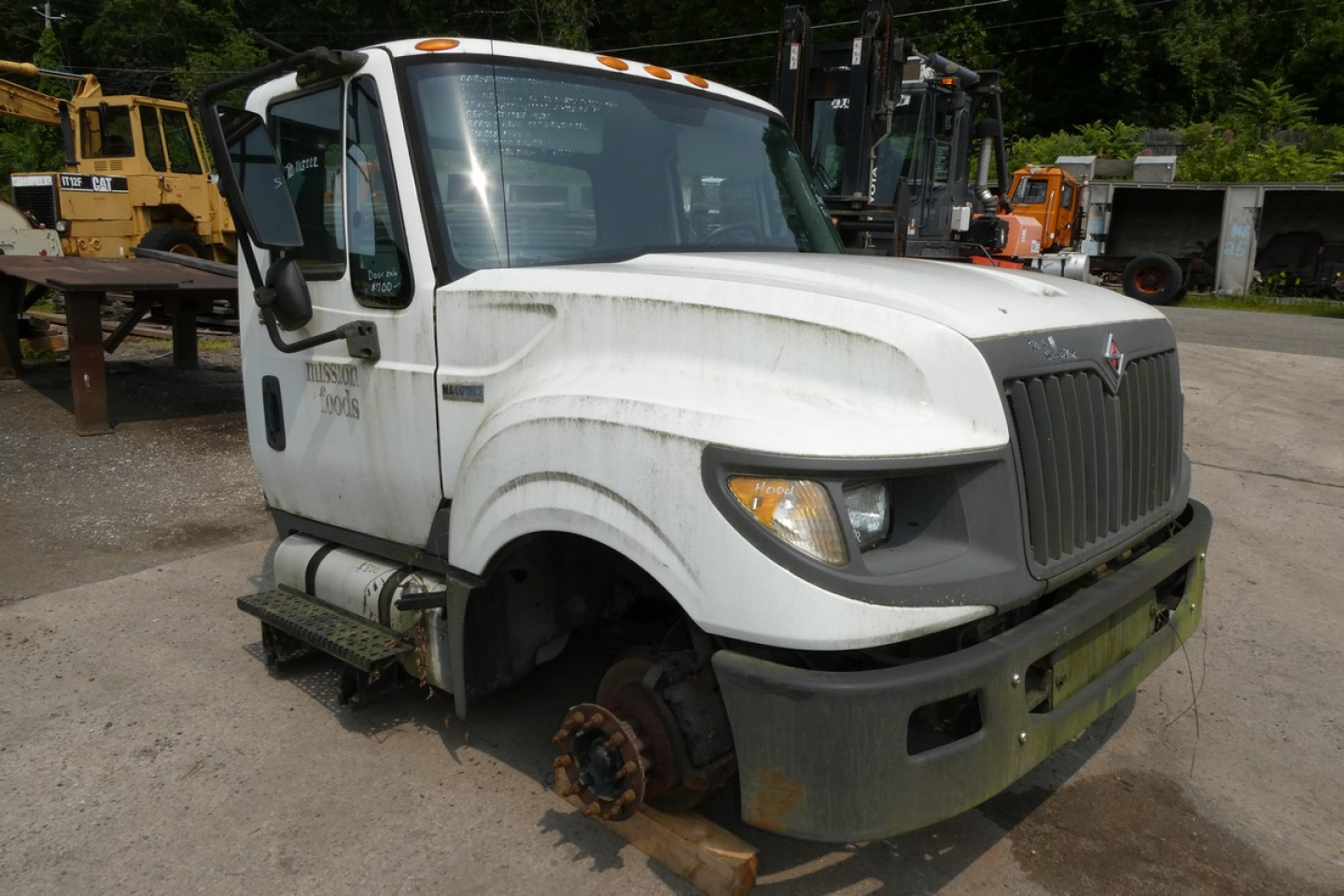 Cab and chassis truck showing front view of 2012 International TERRASTAR with missing front wheel and exposed brake rotor; stock number visible and VIN partially legible.