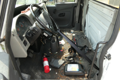Interior of a 2012 International TERRASTAR cab and chassis showing steering wheel, dashboard, and scattered debris on floor; a red fire extinguisher lies near driver’s seat.