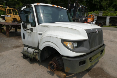 Cab and chassis truck showing front view of 2012 International TERRASTAR with missing front wheel and exposed brake rotor; stock number visible and VIN partially legible.