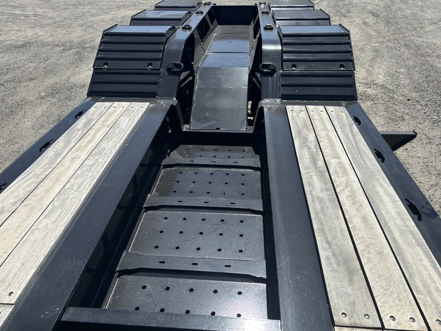 Trailer deck with loaded king lowboy frame showing perforated steps and side decking profiles.