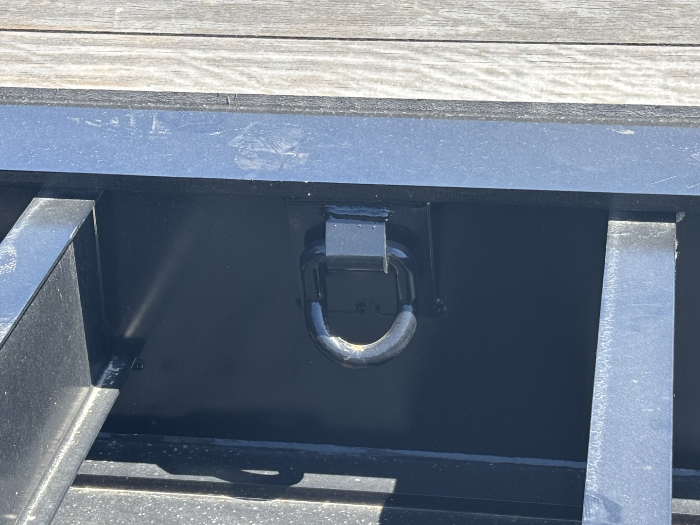 Trailer equipment image showing a load king lowboy hitch ring and accessible toolbox/compartment in a painted metal frame.