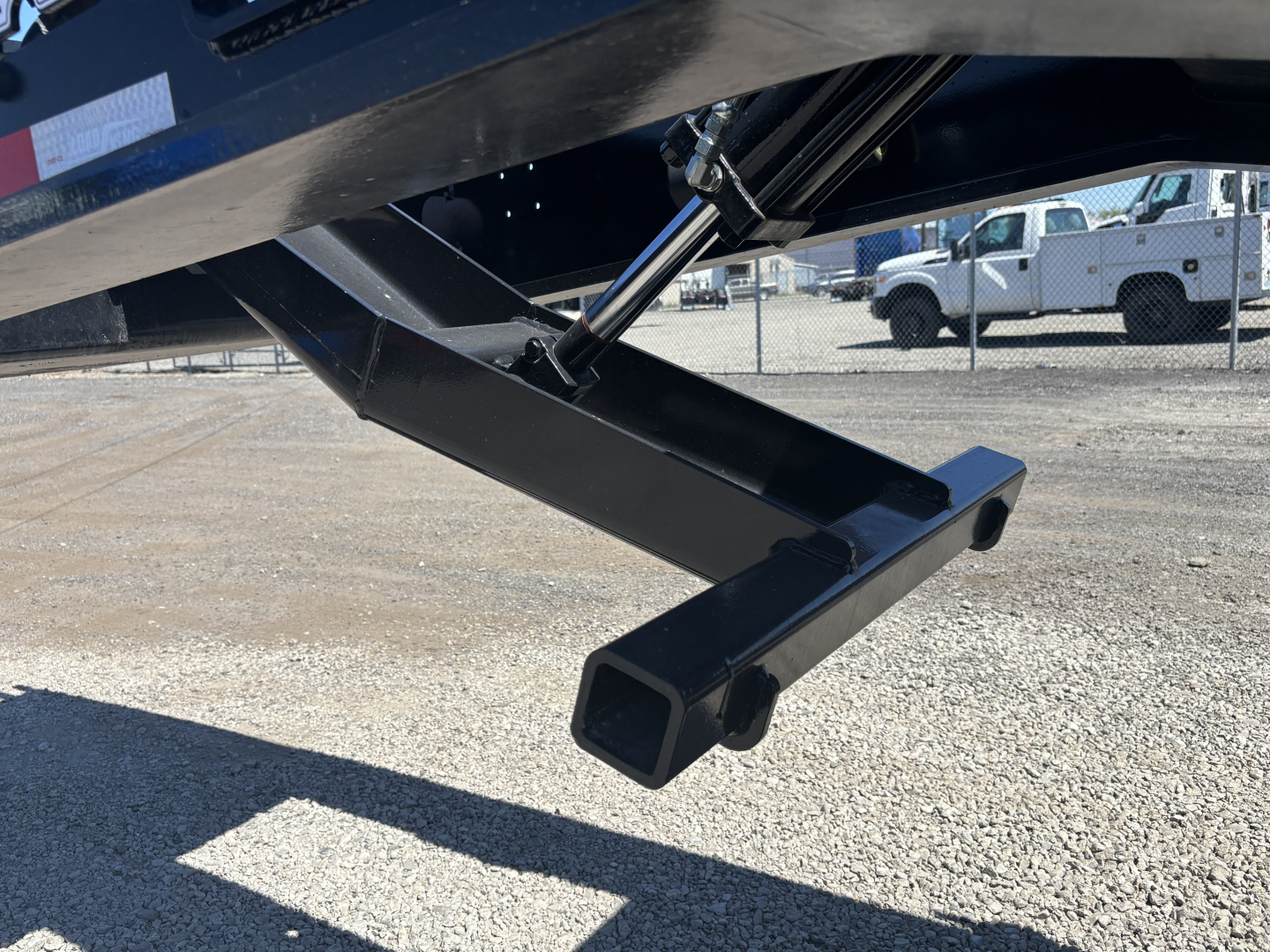 Trailer support leg and hitch area of a Load King lowboy trailer with a square tubular bumper and hydraulic component visible.