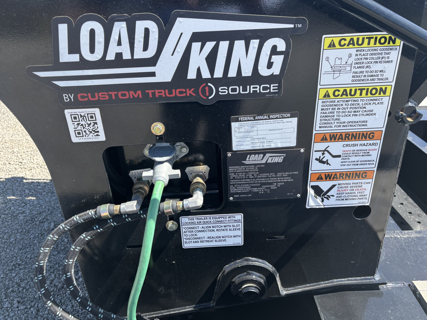 Load King trailer front panel showing hoses, gauges, and warning labels; Load King logo and decals, hoses connected to fittings.