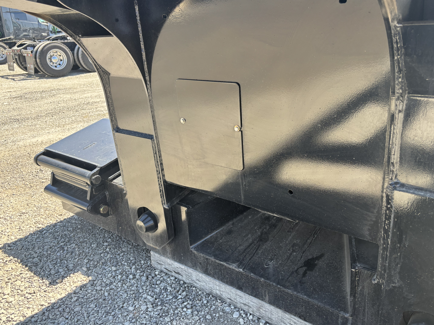 Load King trailer rear corner showing platform steps and access panel with welded metal surface and hitch area.