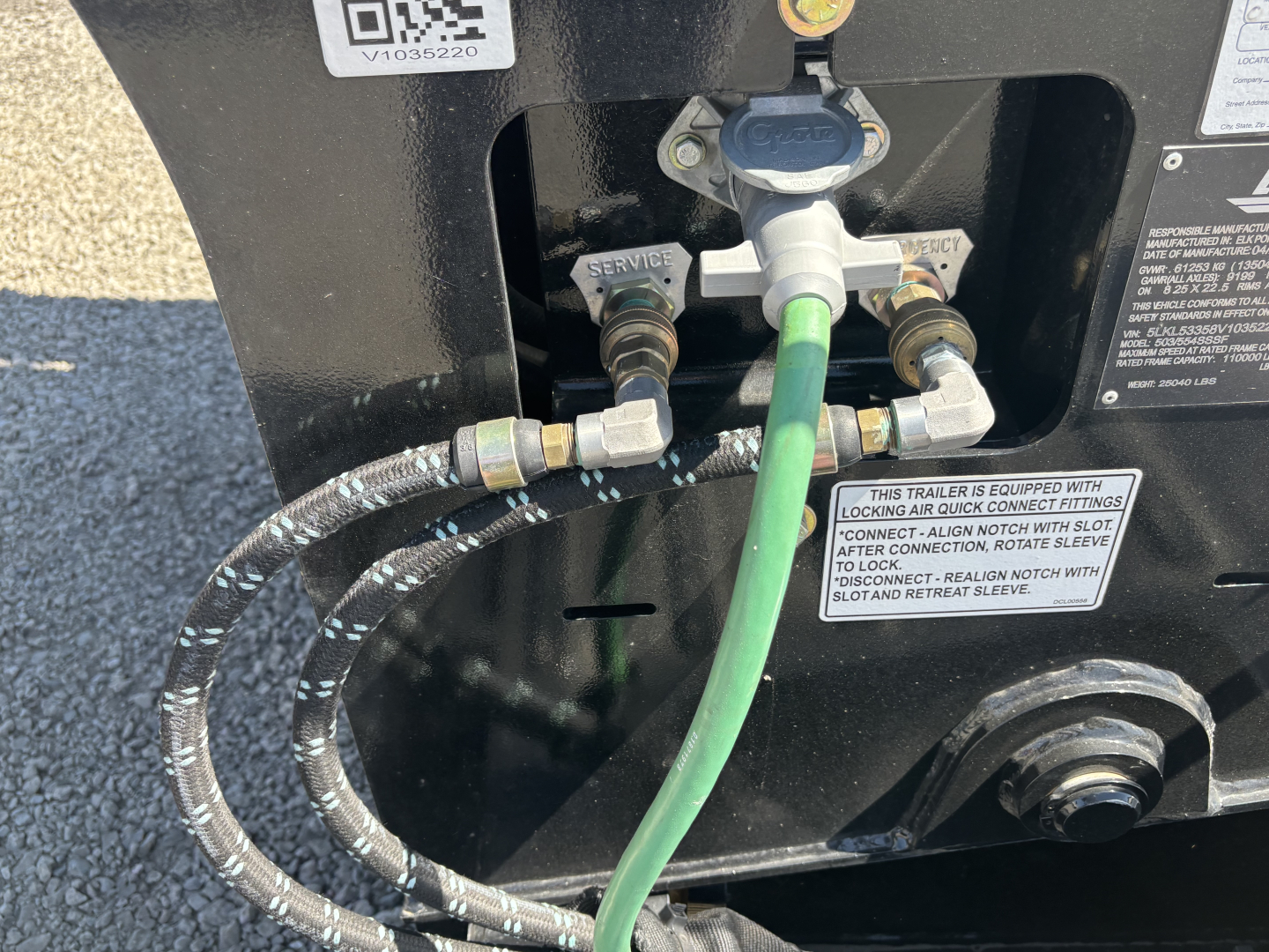 Trailer back showing hydraulic kingpin and connections: green hose connected to relief valve, braided hose with metal fittings, service and lock labels.