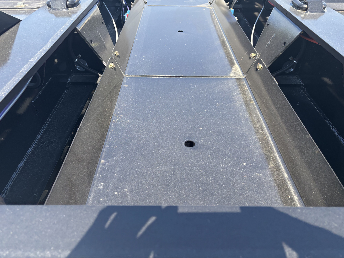 Trailer deck with metal surface and center channel, showing a close-up of the flatbed cross members and side rails.