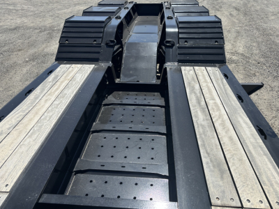 Trailer deck with loaded king lowboy frame showing perforated steps and side decking profiles.