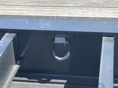 Trailer equipment image showing a load king lowboy hitch ring and accessible toolbox/compartment in a painted metal frame.