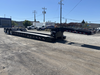 Load King lowboy trailer showing dual-deck extendable sections with gooseneck and ramps extended, black with reflective markings.