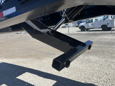 Trailer support leg and hitch area of a Load King lowboy trailer with a square tubular bumper and hydraulic component visible.