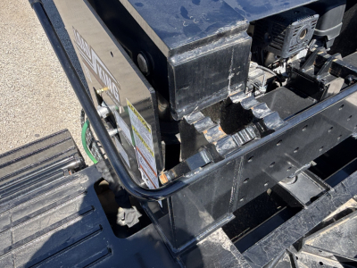 Load King trailer showing chassis and hydraulic components with visible safety labels and wiring harness; multiple rivets and black paint; partial sticker text.