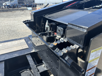 Load King trailer component view showing hydraulic and pin area with caution label, metal frame, and cutouts.