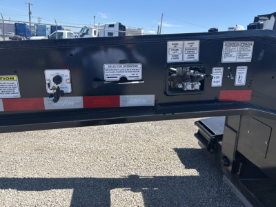 Trailer frame with control labels and selectors on side rail showing operation stickers and gauges.