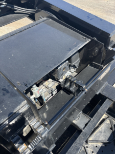 Load King trailer hitch area showing hydraulic battery and control components in an open access panel with black metal framing.