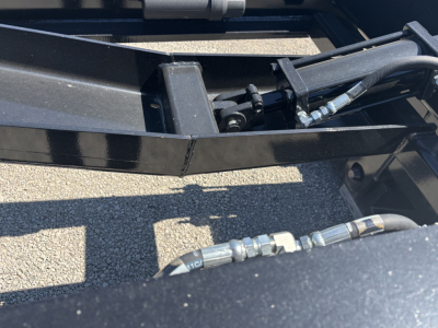 Trailer hydraulic line and hitch area of a Load King trailer showing hoses and fittings with metal frame members.