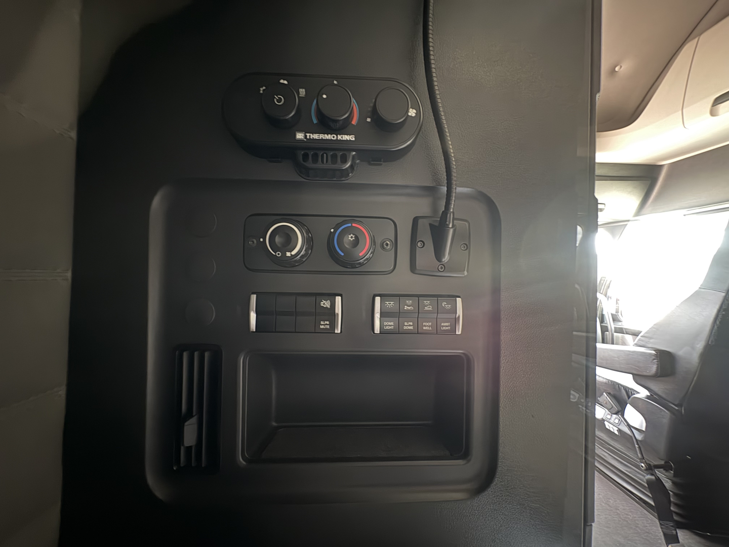 Dashboard controls and center console of a Freightliner Cascadia 126 truck showing HVAC knobs and a small storage area.
