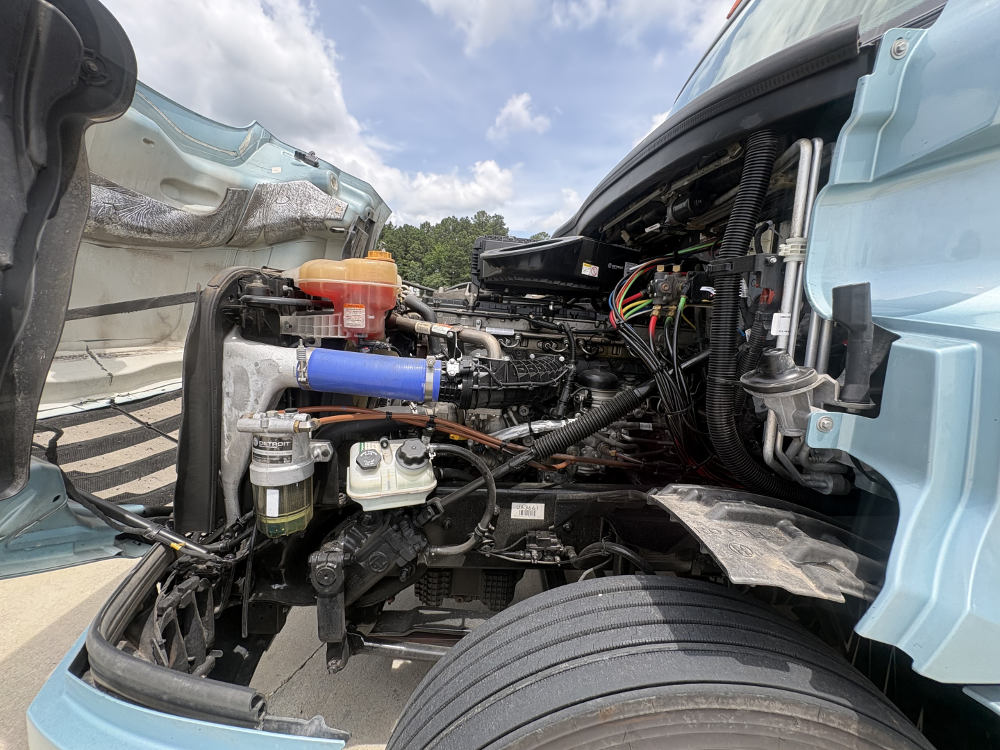 Freightliner Cascadia 126 engine bay showing exposed components, hoses, and wiring near the cab interior.
