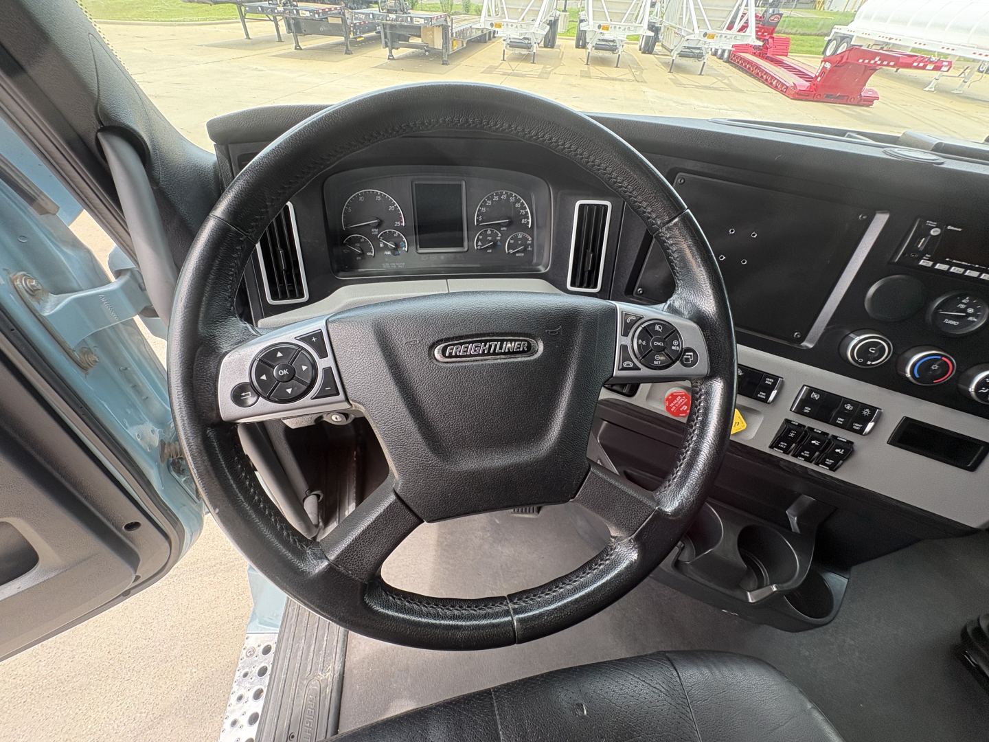 Cab interior of a Freightliner Cascadia 126 with steering wheel and dashboard visible.