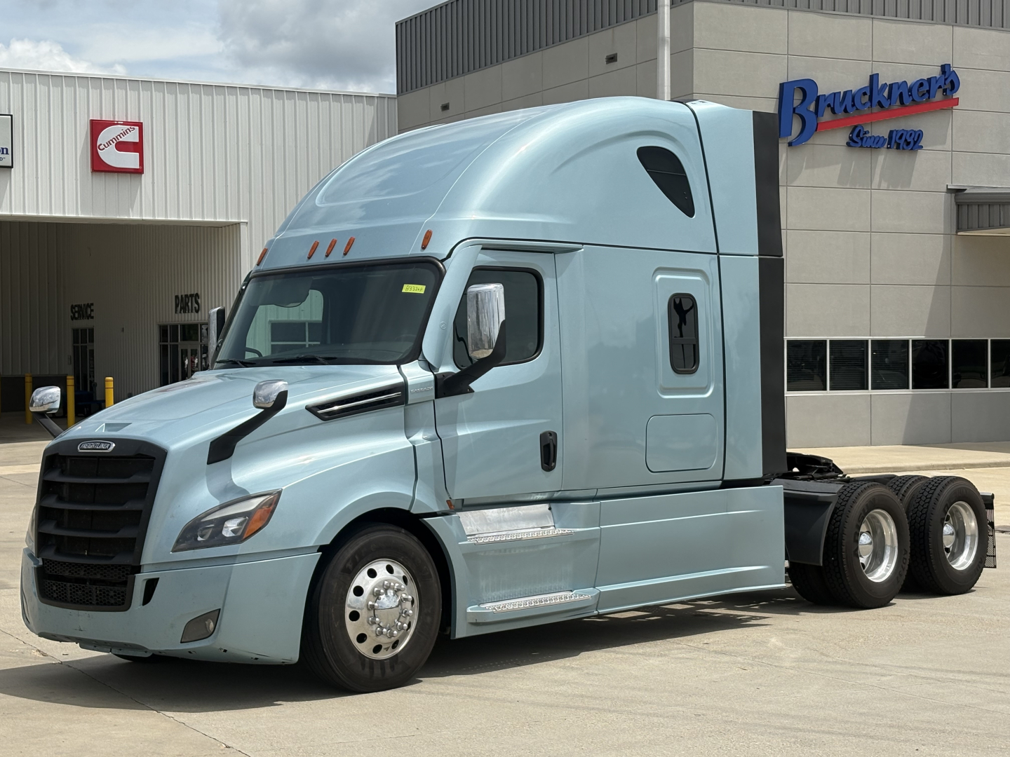 Freightliner Cascadia 126 tractor in light blue parked outside with sleeper cab and twin rear axles.