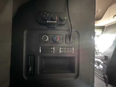 Dashboard controls and center console of a Freightliner Cascadia 126 truck showing HVAC knobs and a small storage area.