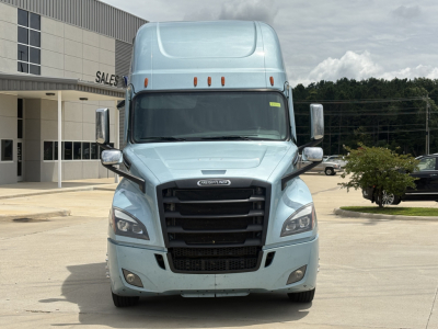 Freightliner Cascadia 126 front view showing blue sleeper cab, black grille, headlights, chrome mirrors, and raised roof in a dealership lot.