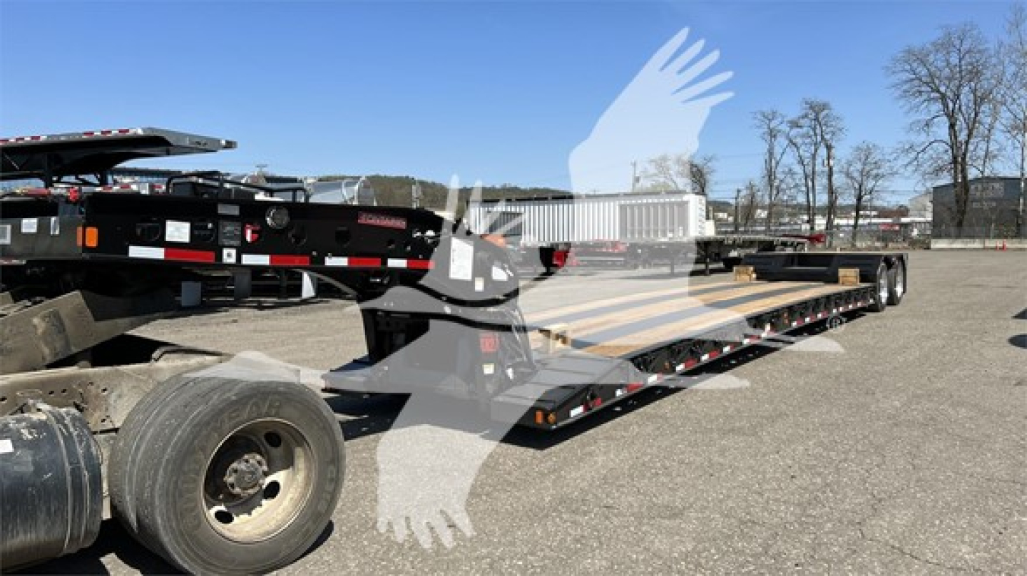 Flatbed trailer in a yard showing a Fontaine Renegade Xn20 lowboy trailer with multiple axles and ramps.