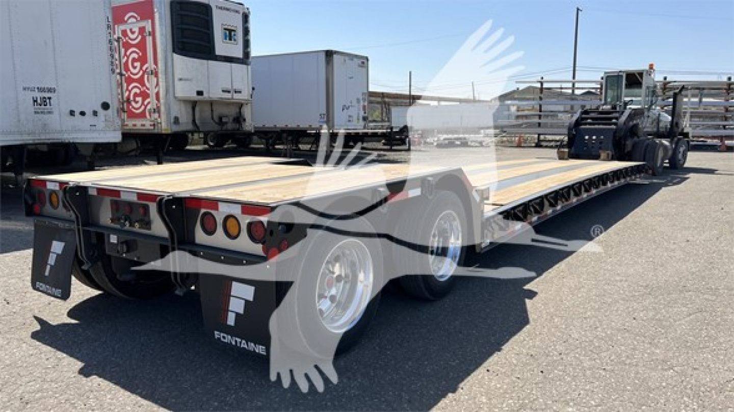 Fontaine Renegade Xn20 lowboy trailer showing wooden deck and dual-axle configuration with wheel fenders and rear lights.