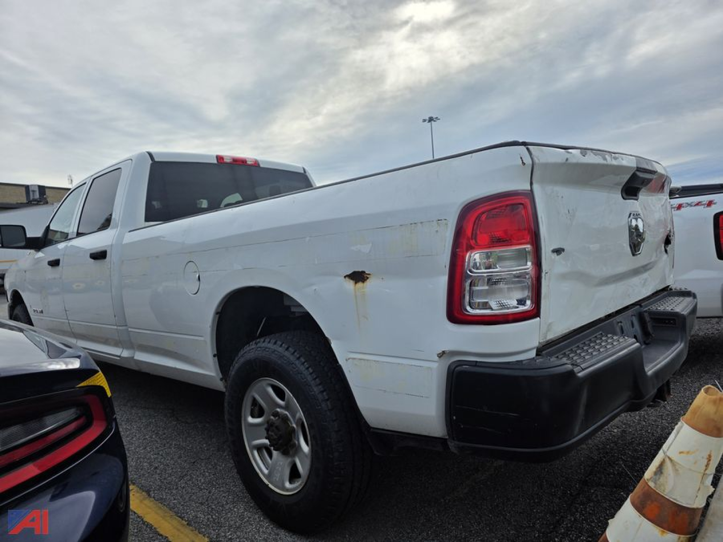 2019 Ram 3500 pickup truck in a lot, white with a crew cab, 4x4, rear tailgate, visible rear right side with rust spot and bumper.