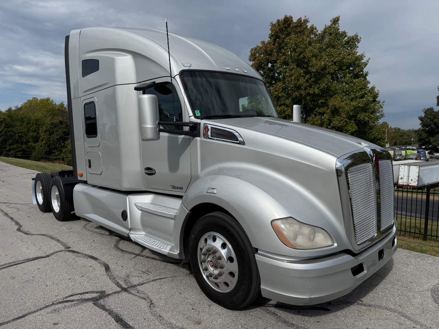 Kenworth T680 sleeper cab tractor front-left view showing chrome grille, headlights, and silver exterior with aerodynamic mirrors.