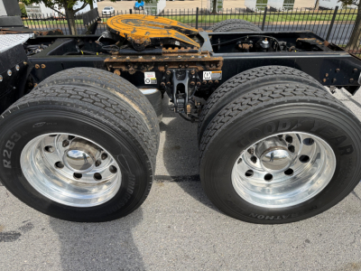 Kenworth truck chassis twin rear axles with two large wheels, chrome rims, rust-prone frame, fuel/tank area and fifth-wheel mounting plate visible.