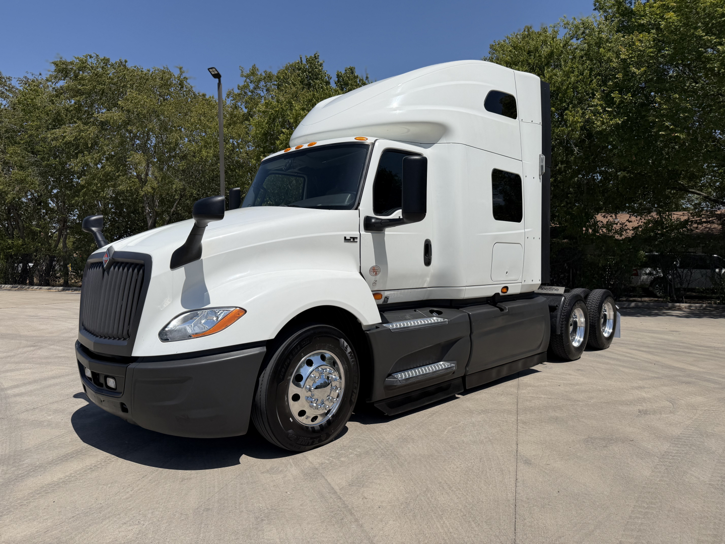 International LT625 truck cab and chassis in white, side view, with sleeper cab profile and dual rear axles.