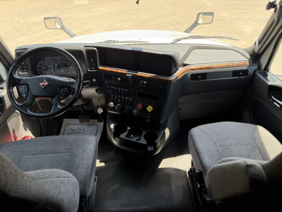 Truck cab interior showing steering wheel, dashboard, and center console with gear shifter and cup holders.
