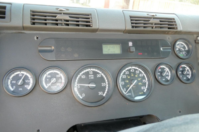 Dashboard panel of a 2012 Freightliner Cascadia 125 showing multiple gauges and a small digital display in the center.