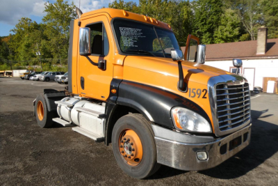 Freightliner Cascadia 125 daycab truck in orange and black, front-left angle, with stock number 0925255 and ID 1592 visible on door, used condition.
